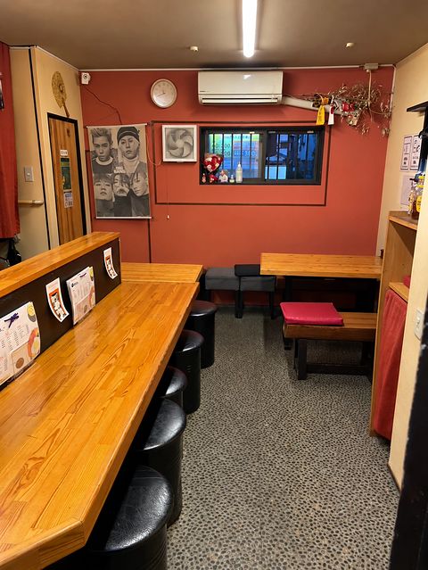 奥まで続く木のカウンターと、ポスターや時計のある赤茶色の壁の店内