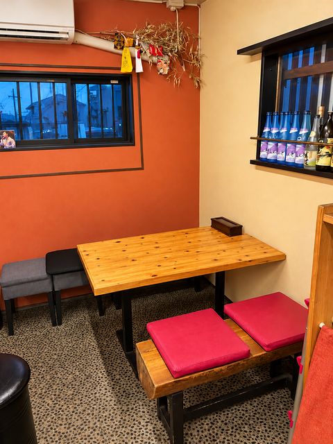 Wooden table under the window, with a red-cushioned bench